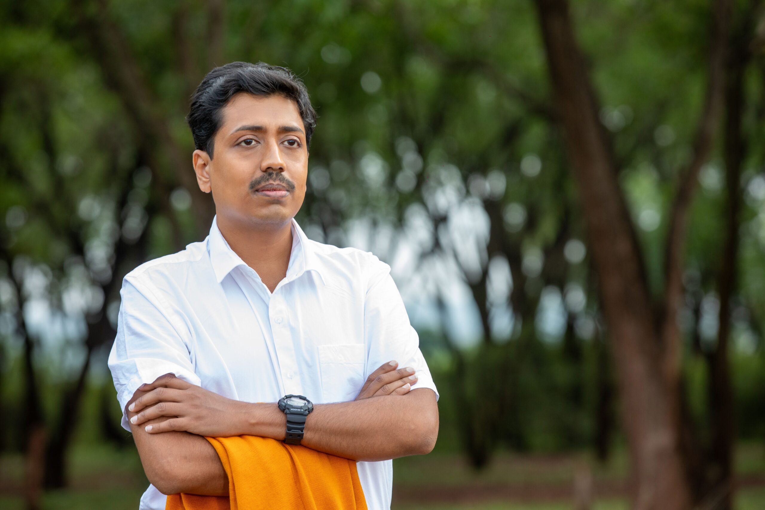 Portrait of a confident man outdoors in a casual pose with an orange shawl.